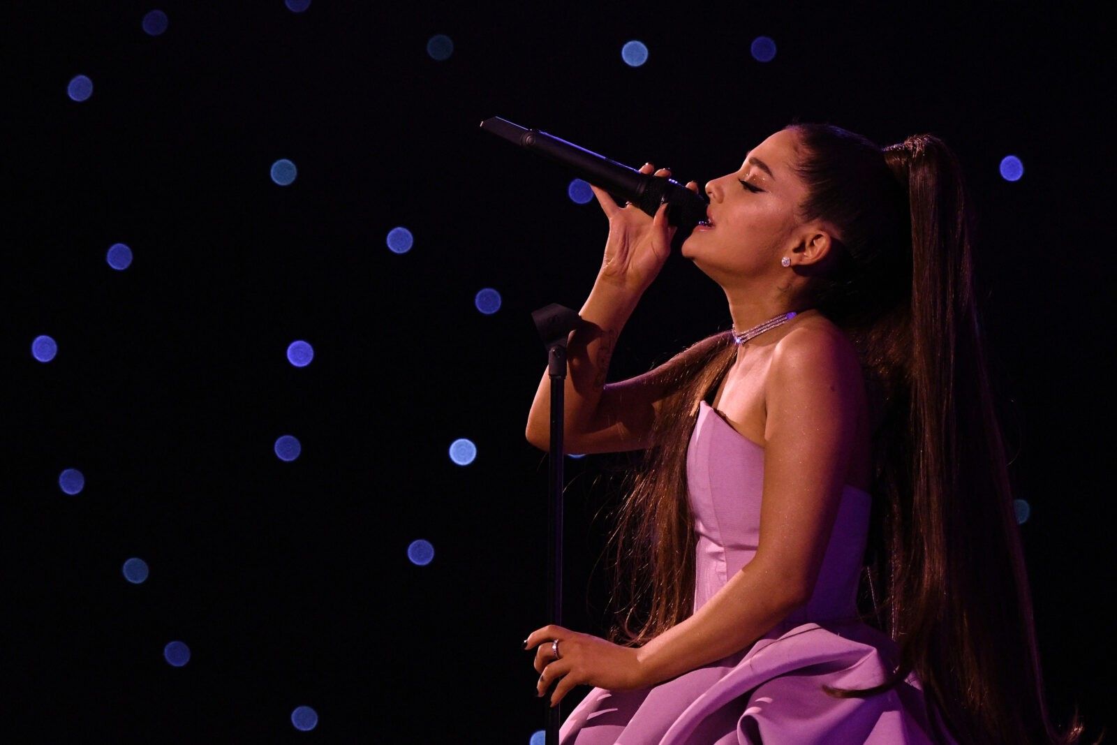 Ariana-Grande wearing a pink dress while performing on stage.