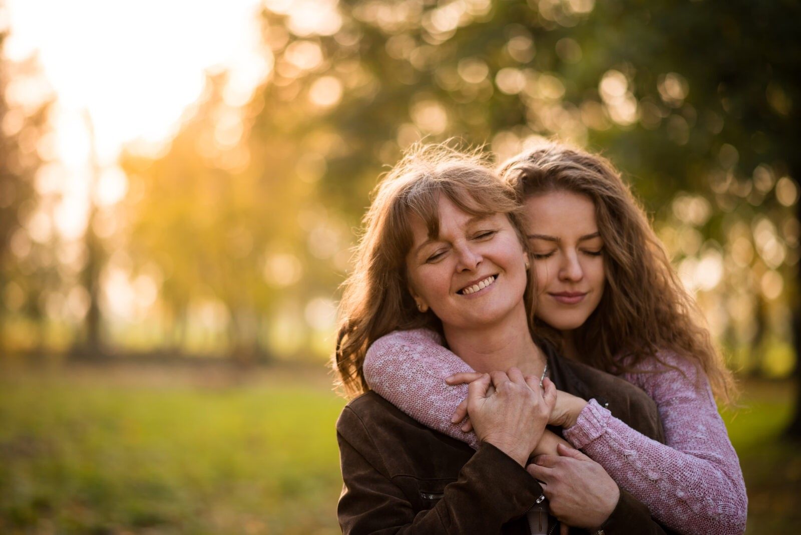 Teen woman embracing mother with closed eyes