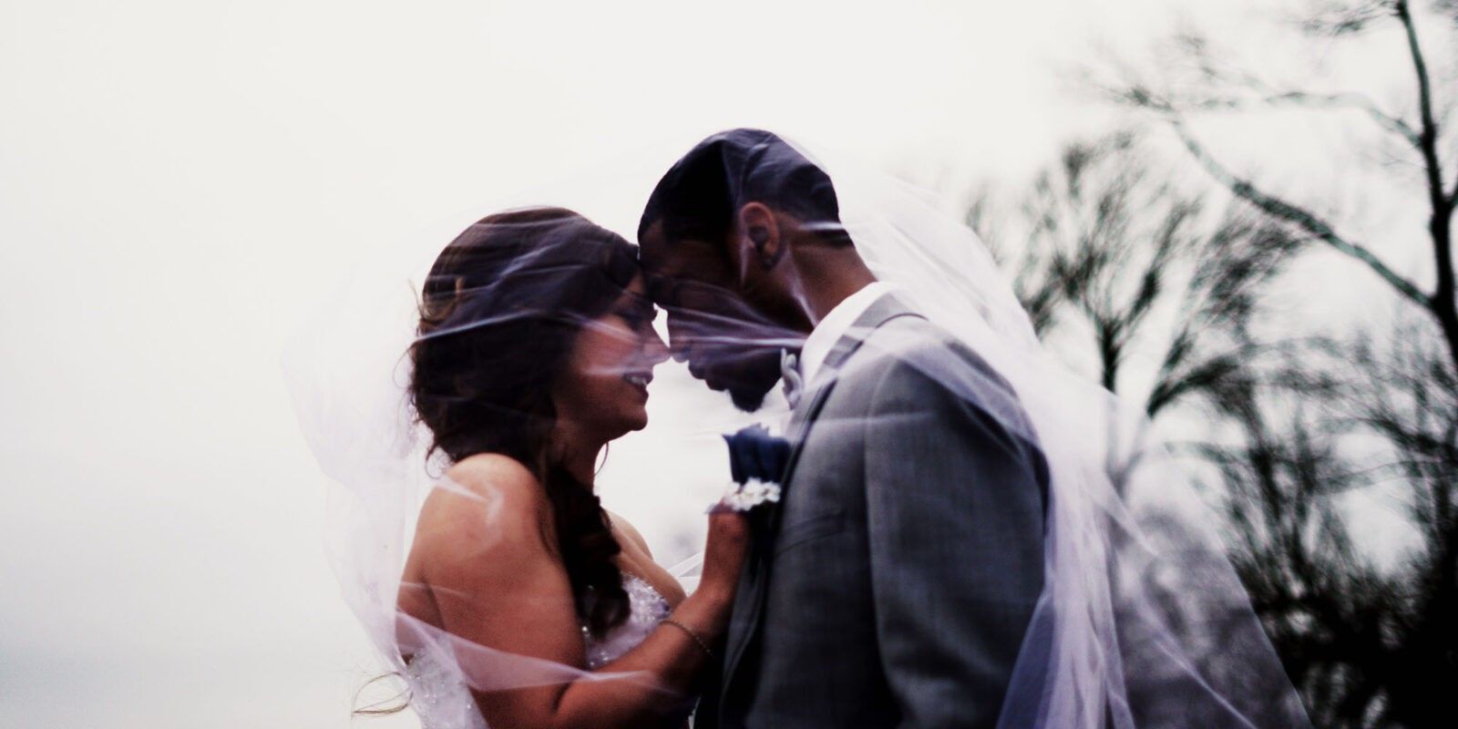 Bride and groom in front of each other under veil