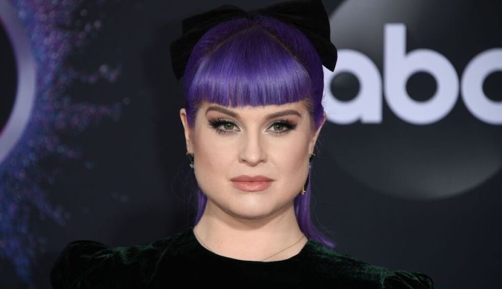 Kelly Osbourne with purple bangs looking at the camera.
