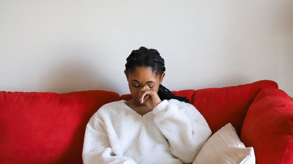 Woman in a white shirt cries on a red couch