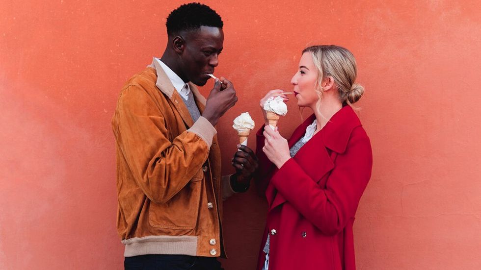 Man and woman having ice cream together, smiling facing each other