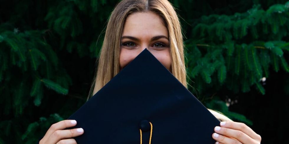 Girl smiling, hiding face behind graduation cap by Evan Mach on Unsplash