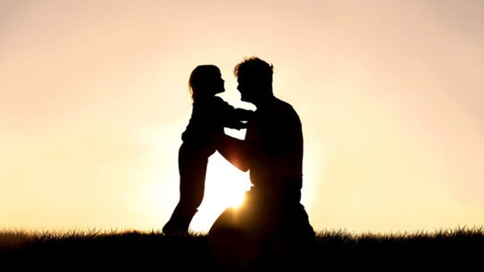 Father and daughter silhouette playing at sunset