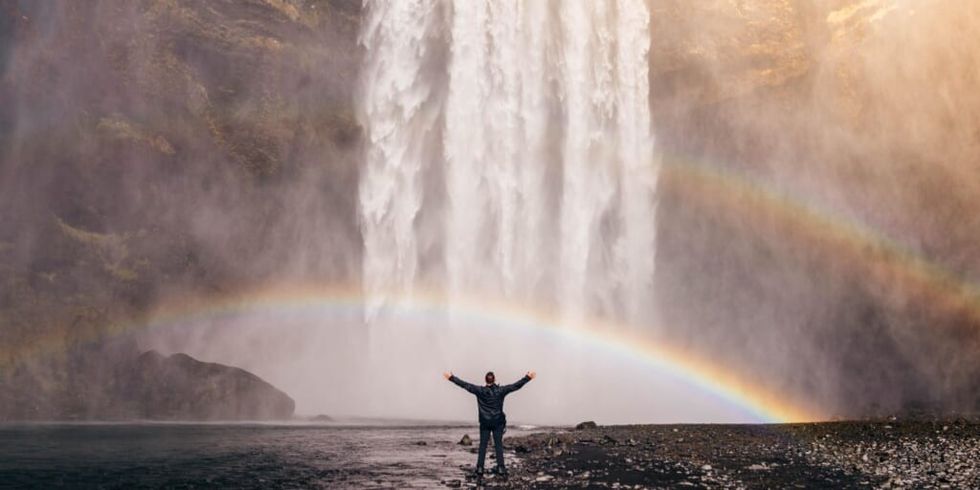 Man standing in front of waterfall with double rainbow by Jared Erondu on Unsplash