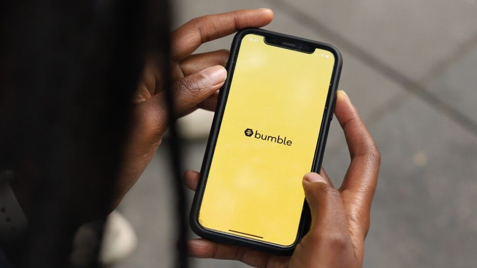 A Black woman uses the Bumble app on her phone