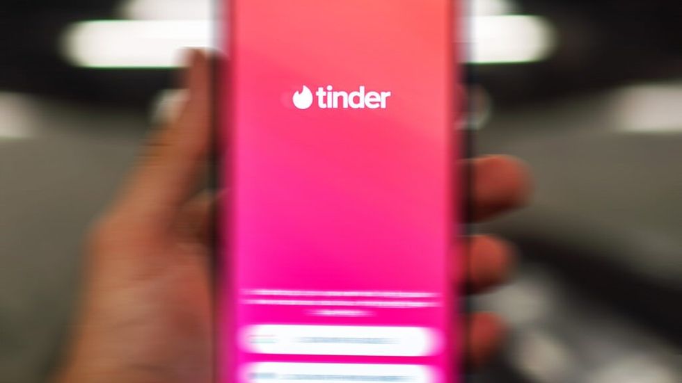 Blurred hand holding a phone using the Tinder app
