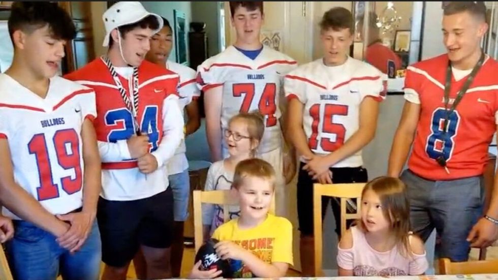 High school football team sings happy birthday to young boy and girl