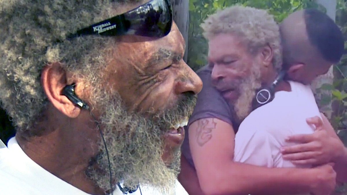 Homeless man smiles at he and his son hugging