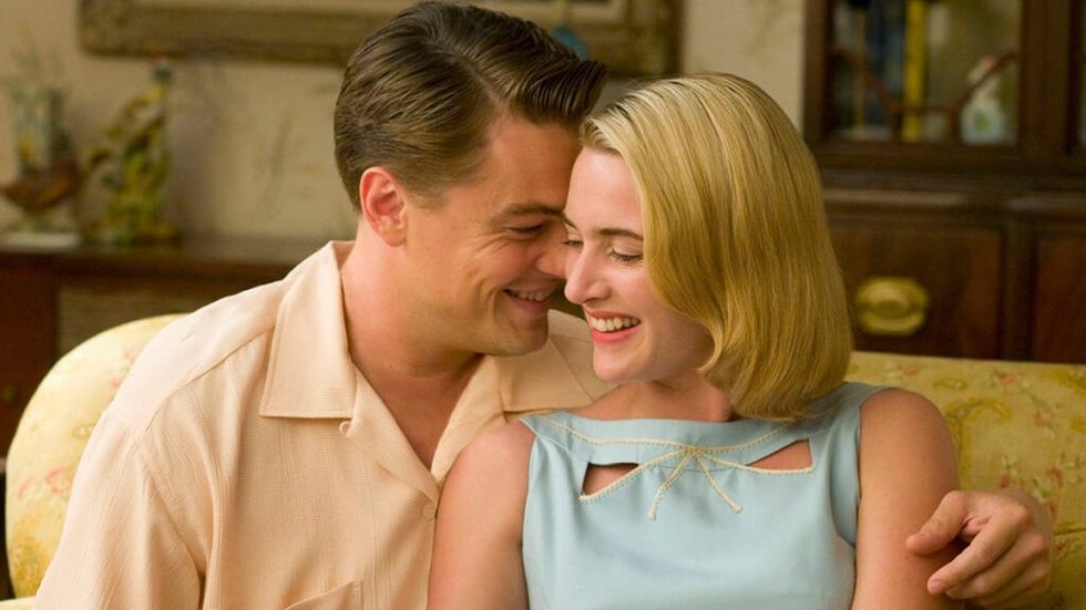 Leonardo DiCaprio and Kate Winslet smiling on a couch in Revolutionary Road