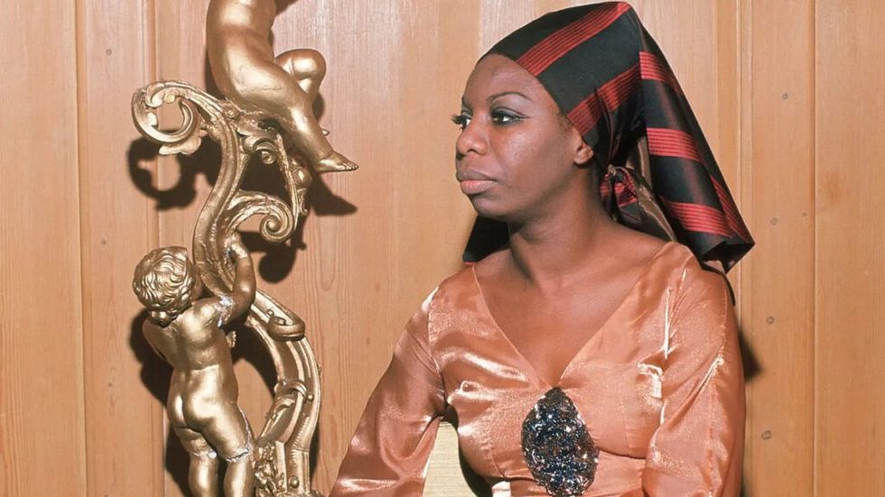 Nina Simone ในชุดหรูหราและผ้าโพกศีรษะใกล้รูปปั้นเครูบ