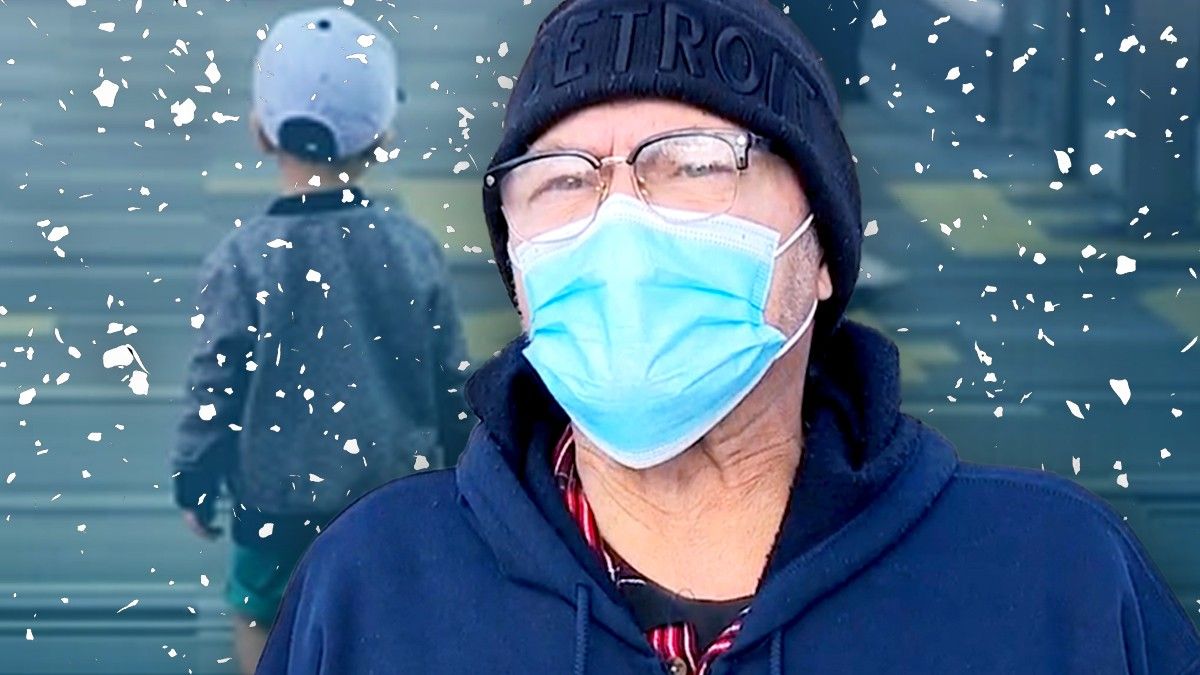Old man in mask stands in front of snowstorm with toddler