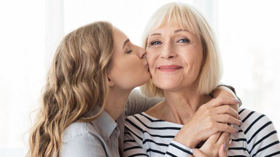 Young adult daughter kissing elderly mother