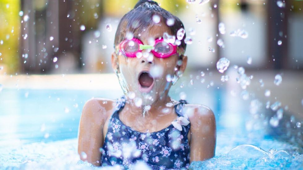 Young girl wearing pink goggles in swimming pool