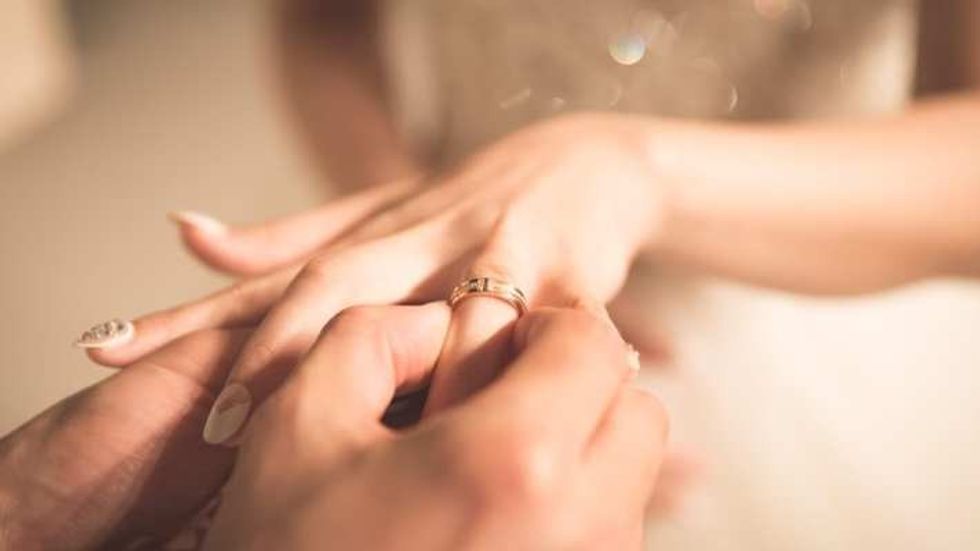 Groom placing ring on bride's finger by Jeongim Kwon on Unsplash