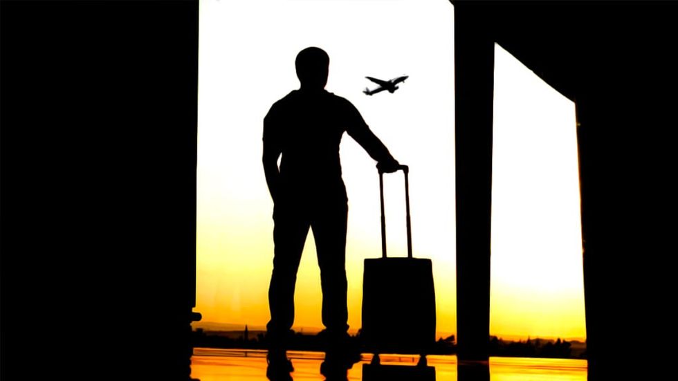 Silhouette of man watching plane take off from airport