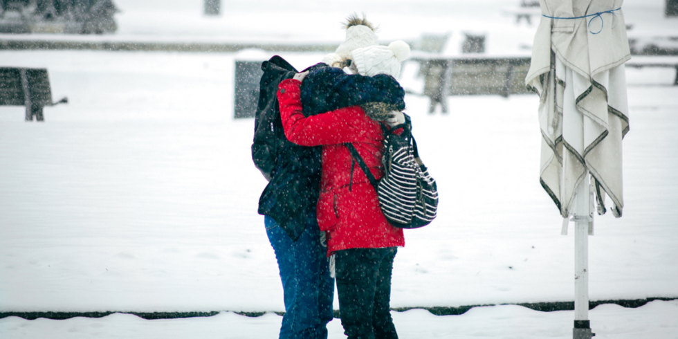 Doi oameni îmbrățișați în zăpadă