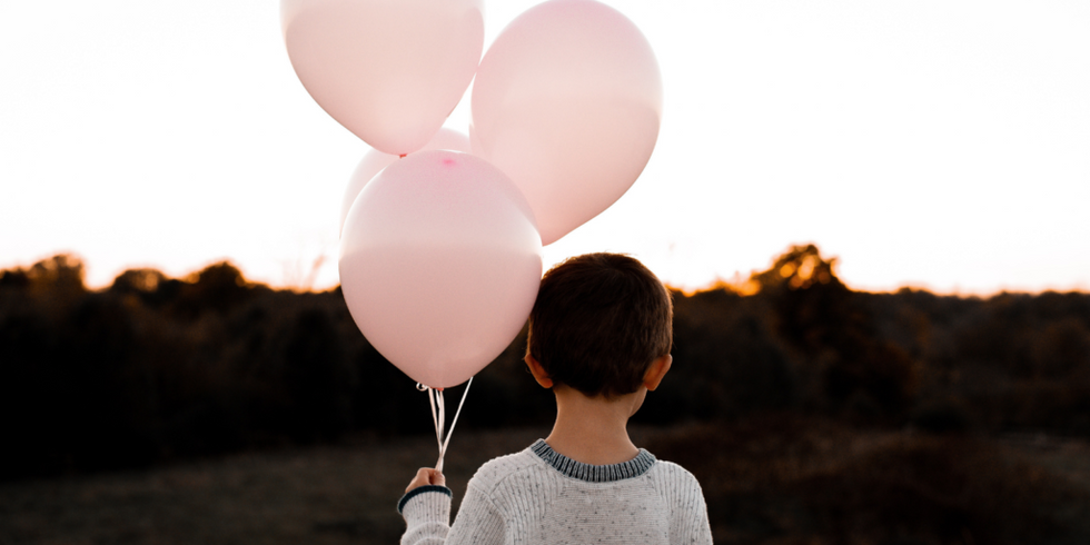 little boy holding 4 pink balloons