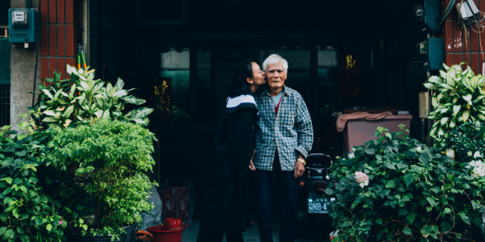 woman kissing elderly man on the cheek