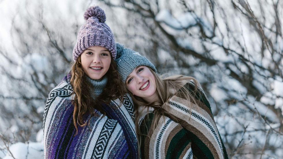Două fete purtând o cască stând în zăpadă