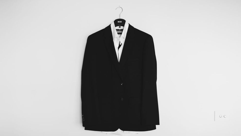 a black tuxedo hanging on a white wall