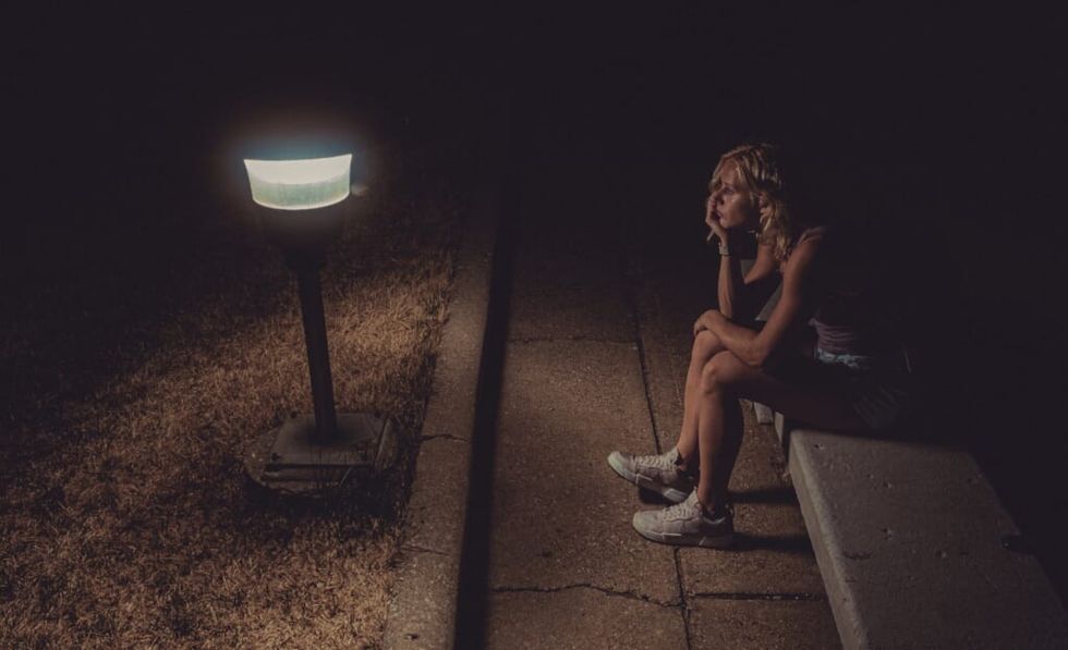 young woman sitting on bench at night