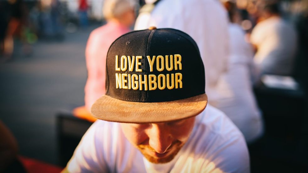 man wearing a yellow and black hat with "love your neighbour" written 