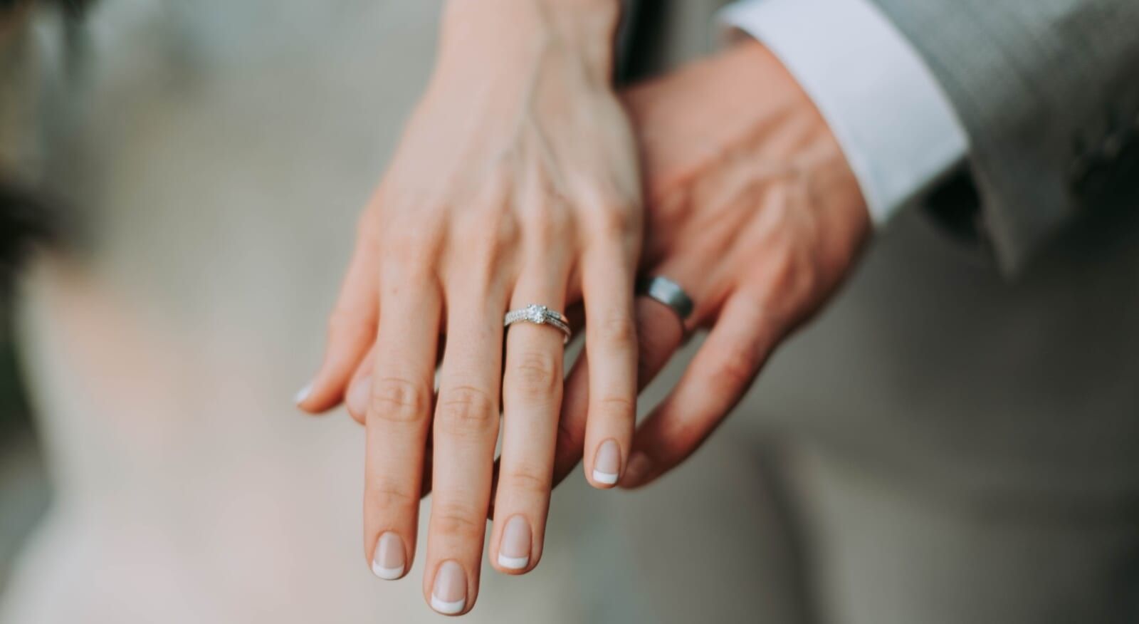 two hands wearing wedding rings hold each other