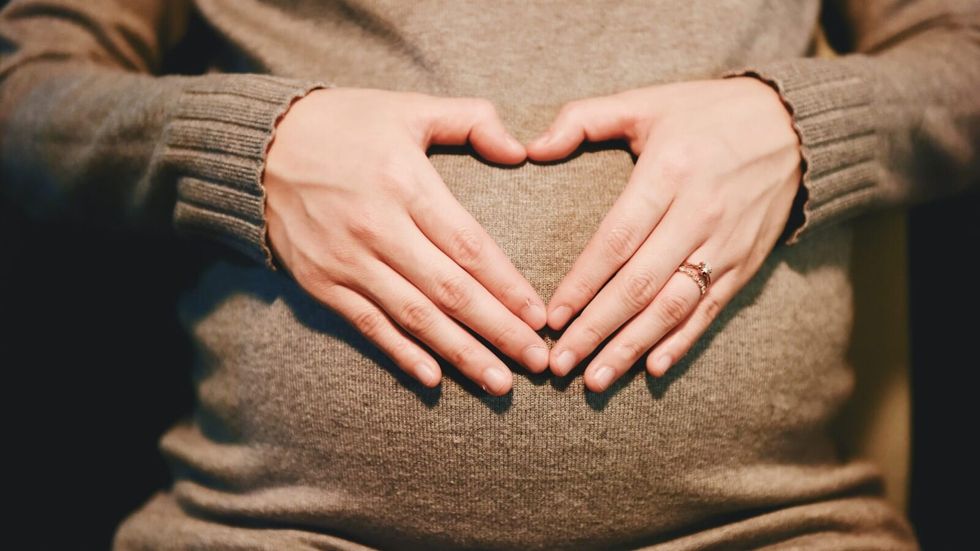 pregnant woman making a heart over her stomach