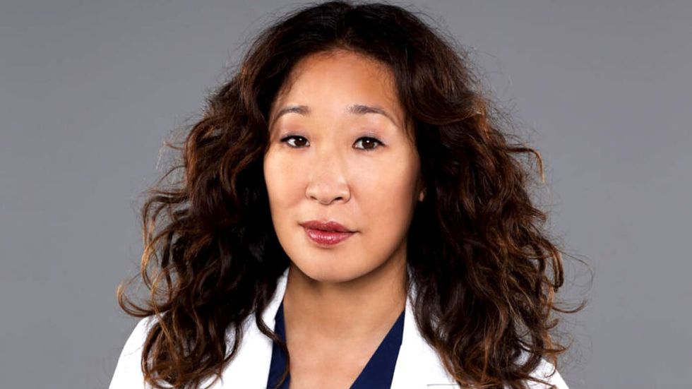 Cristina Yang smiling in a Grey's Anatomy cast shot