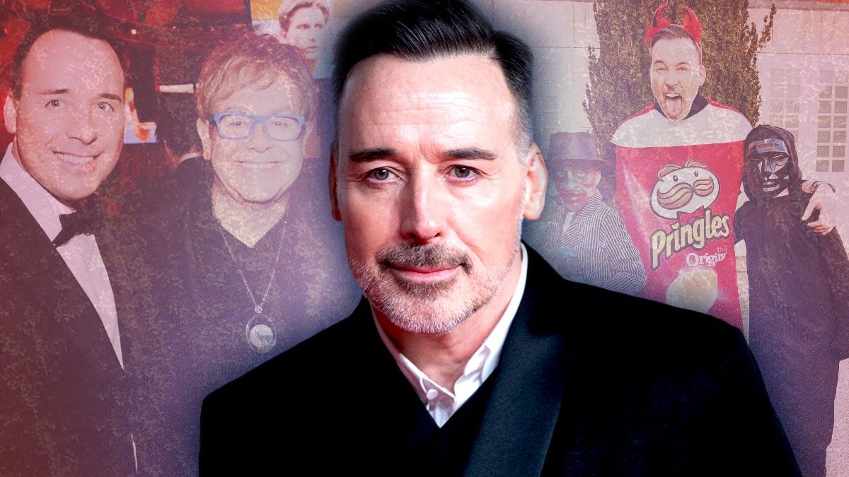 David Furnish smiling in front of photo with husbdand Elton John and their kids