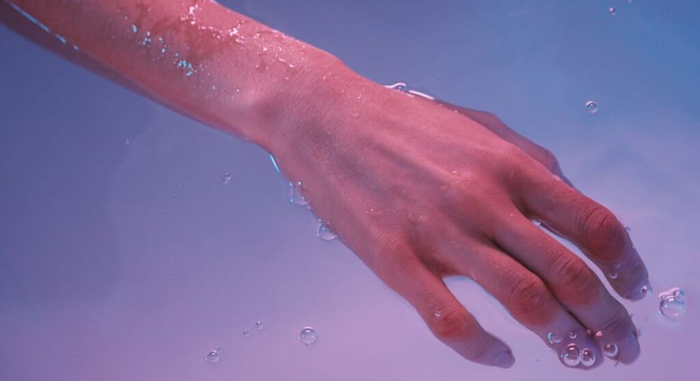 Die Hand der jungen Frau schwimmt im Whirlpool oder im Schwimmbad, sie fühlt sich sehr wohl