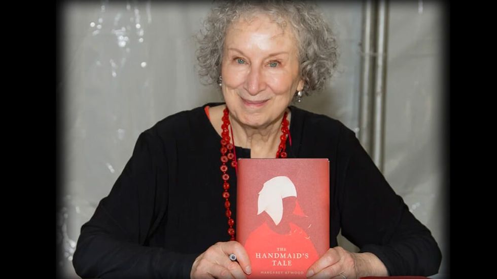 Margaret Atwood holding a copy of a Handmaid's Tale