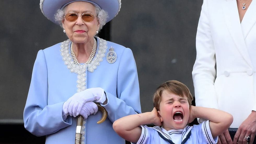 Queen Elizabeth smiling as Prince Louis covers ears