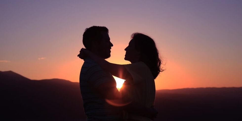 Siluetă a unui cuplu care se ține unul pe celălalt uitându-se în ochi la apus de soare de Oziel Gomez pe Unsplash