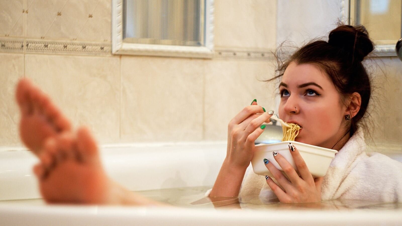 young woman eating noodles in the bath tub