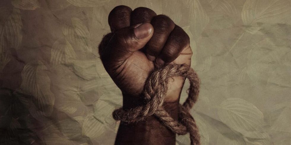 black man's fist with rope tight around by Tasha Jolley on Unsplash