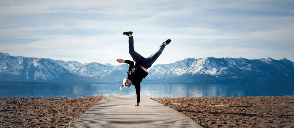 one handed hand stand on dock near mountains