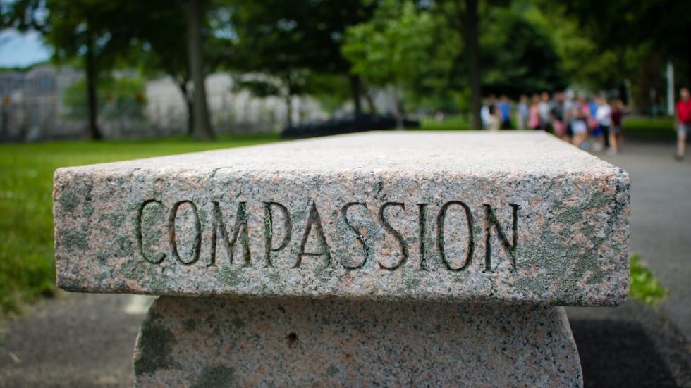 the word "compassion" written on a stone bench