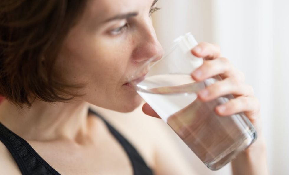 femeie care bea un pahar cu apă