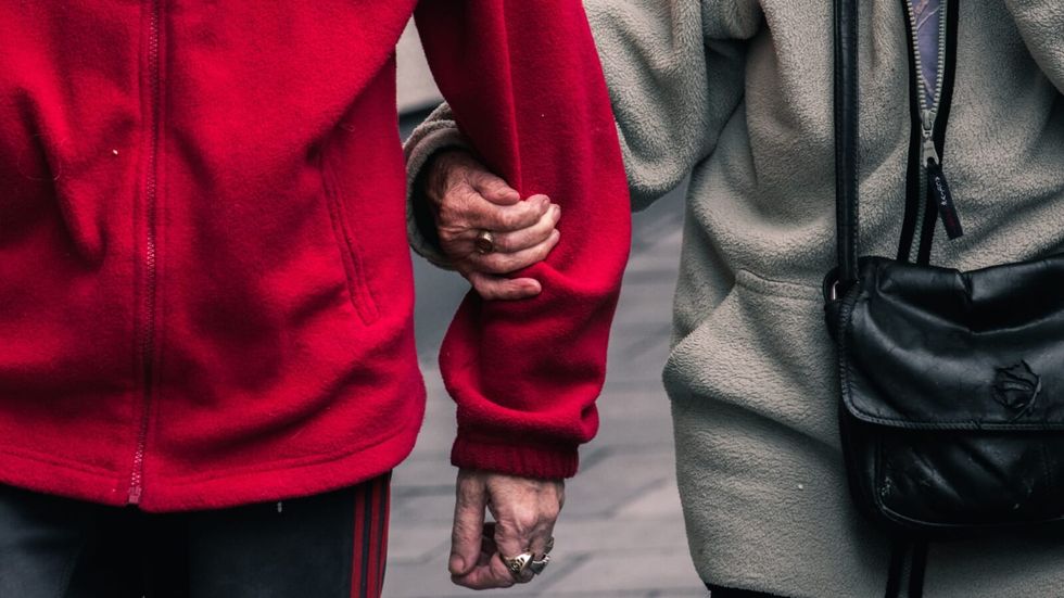 a person in a grey jacket holds on to a person in a red jacket