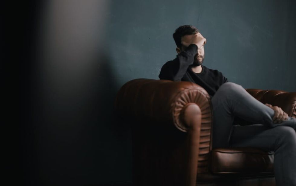 depressed man sits on brown leather couch