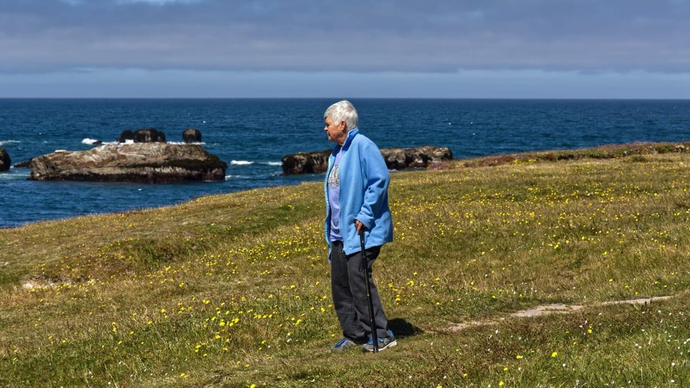 elderly woman standing alone on green grass