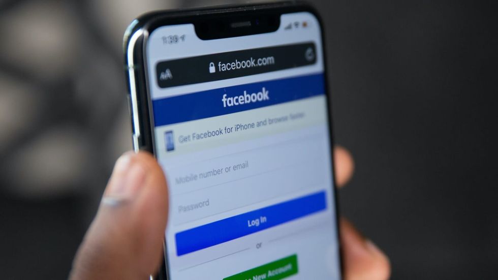 person holding a phone with the facebook app open