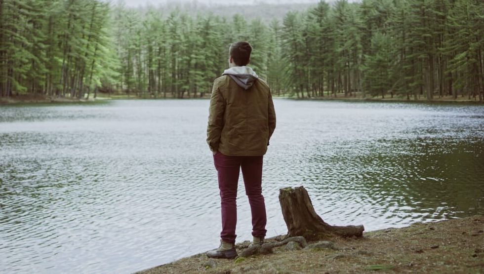 Un bărbat care se gândește la viață și are vedere la un lac