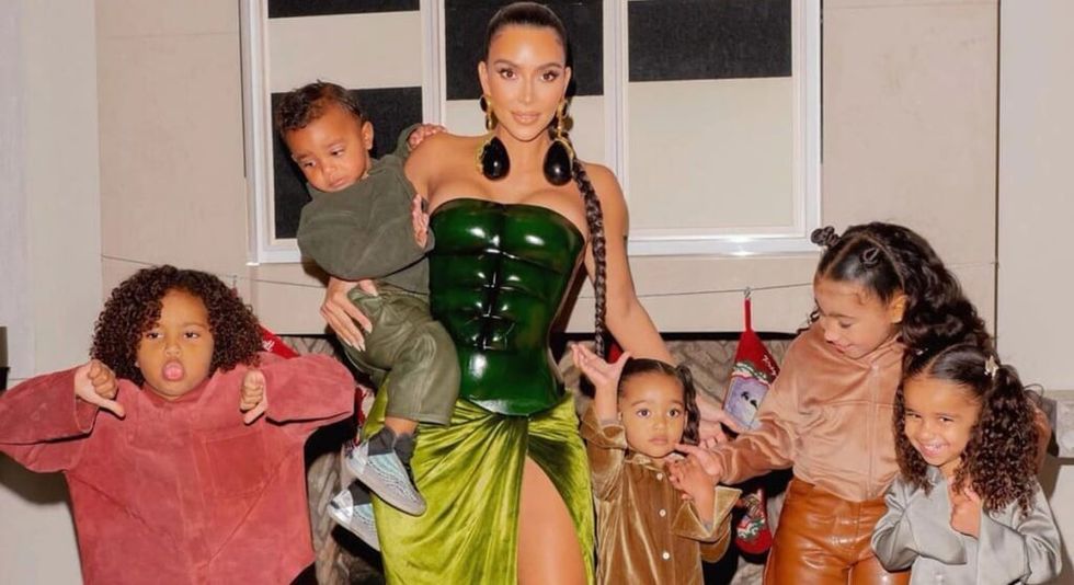 Kim Kardashian cu copii ținându-se de mână și pozând în fața camerei.