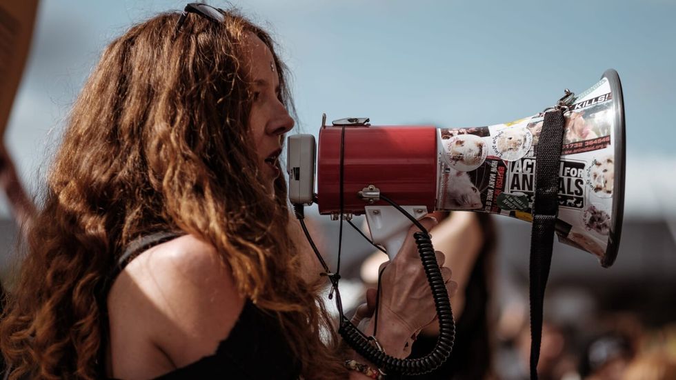 woman speaking into a loudspeaker at a rally