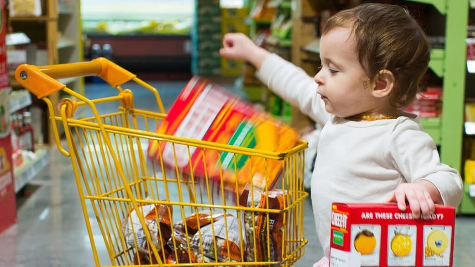 little child putting food into a yellow shopping cart