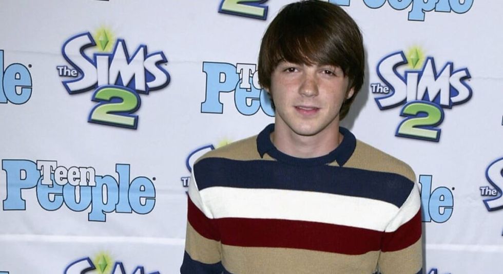 Young Drake Bell in striped sweater on red carpet.
