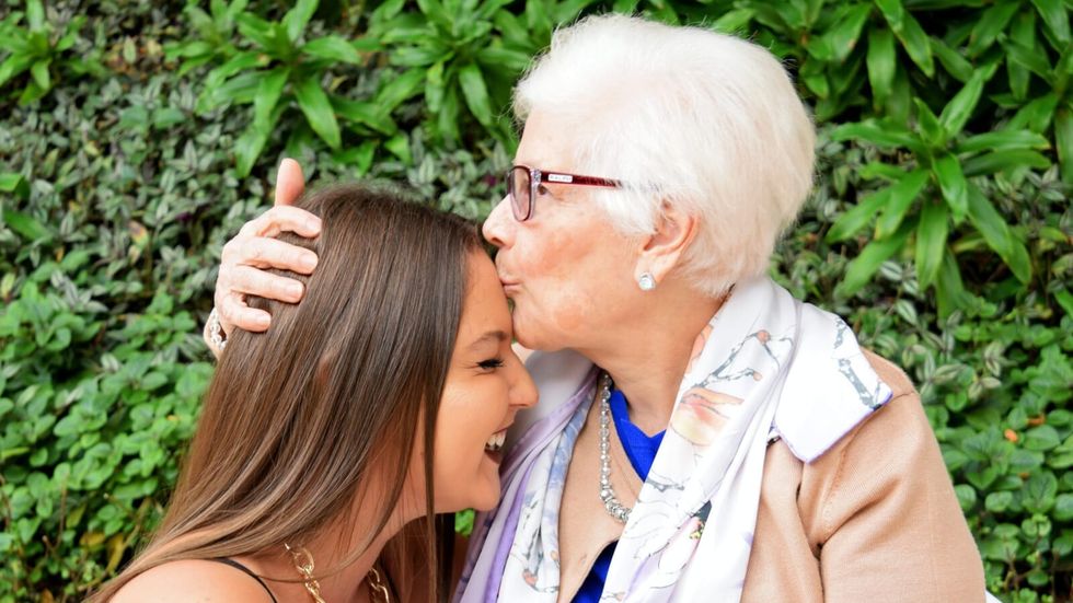 elderly woman kissing young woman's forehead